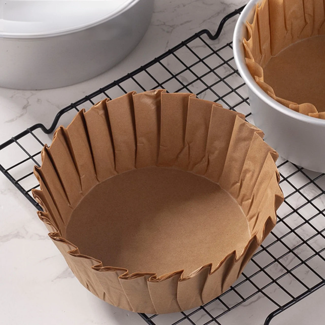 Chemises en papier de couleur naturelle pour gâteau basque dans des moules sur une grille de refroidissement.
