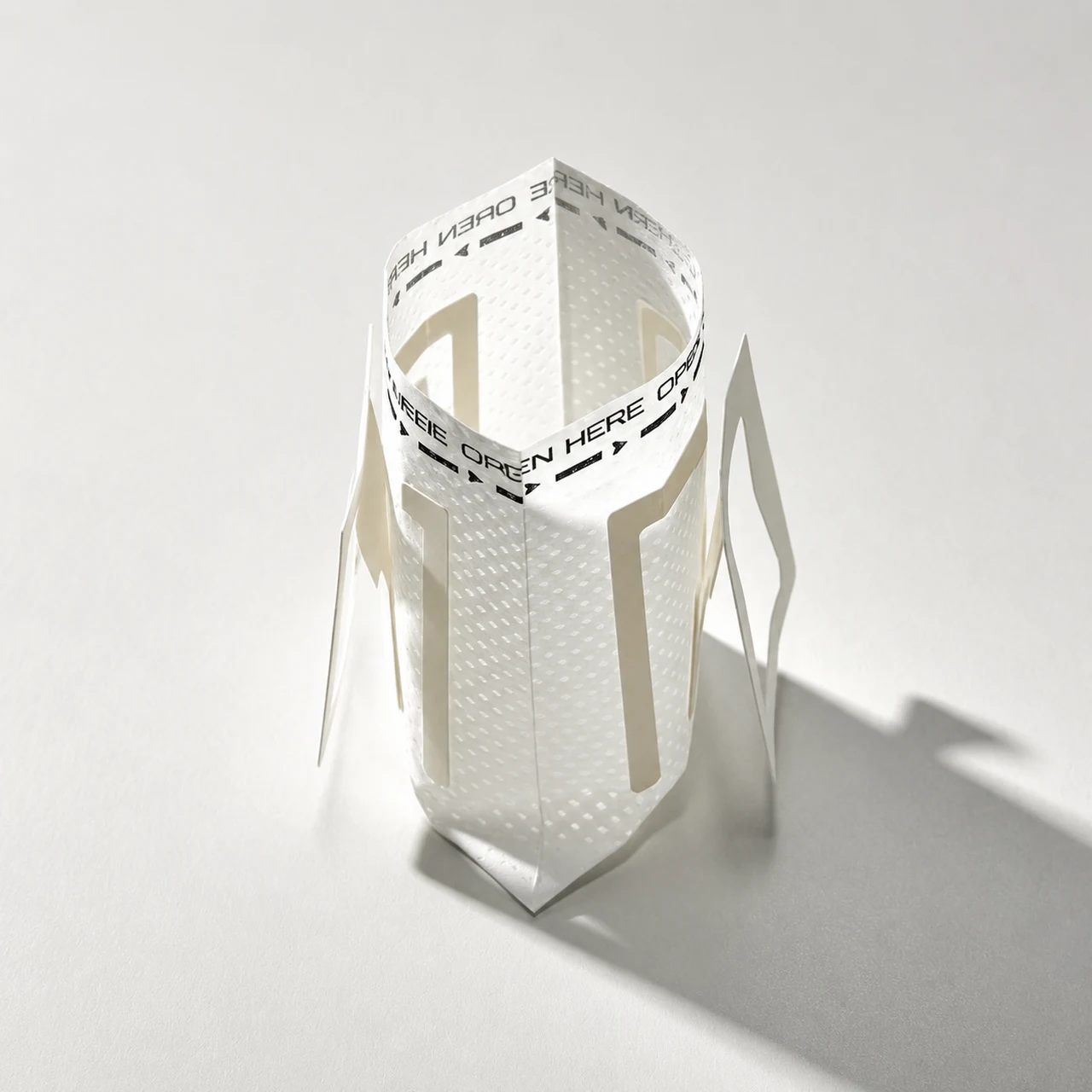 Opened white drip coffee filter bag with its paper supports extended.