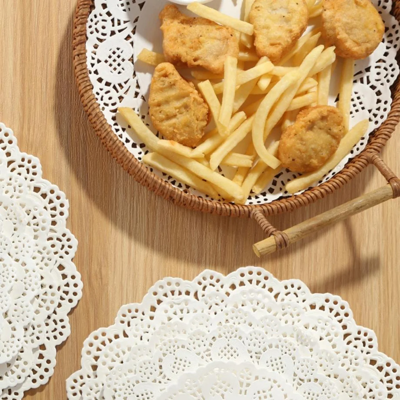 Napperons blancs ajourés tapissant un panier de frites et de poulet frit.