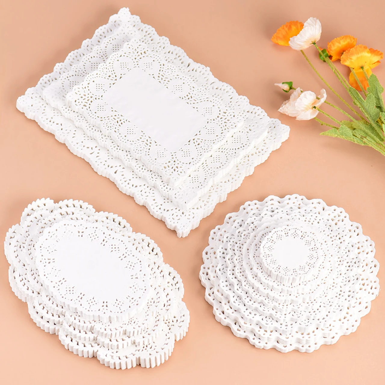 Napperons blancs ajourés ronds, ovales et rectangulaires disposés sur fond pêche.