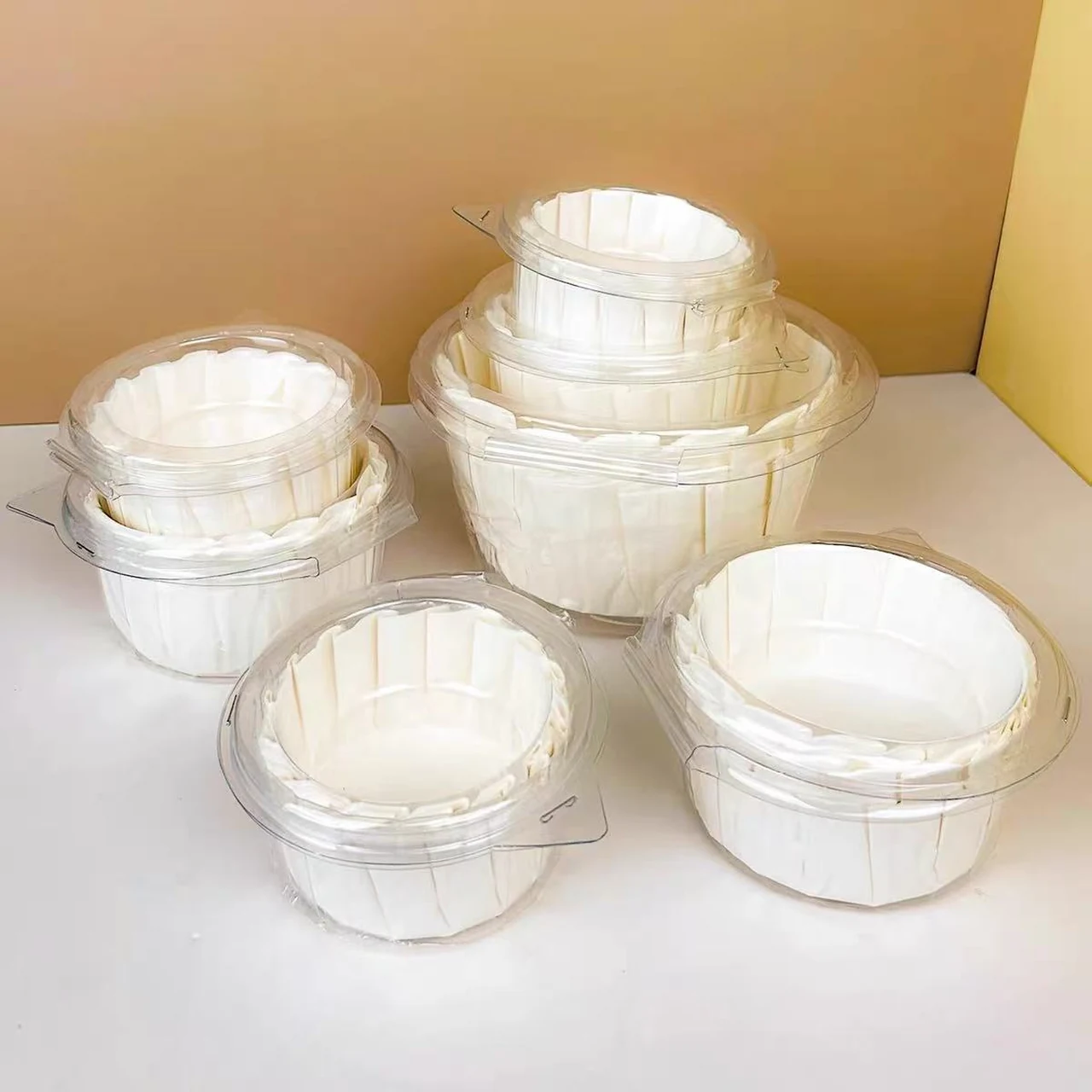 Chemises en papier blanc pour gâteau basque dans plusieurs emballages transparents à charnière.