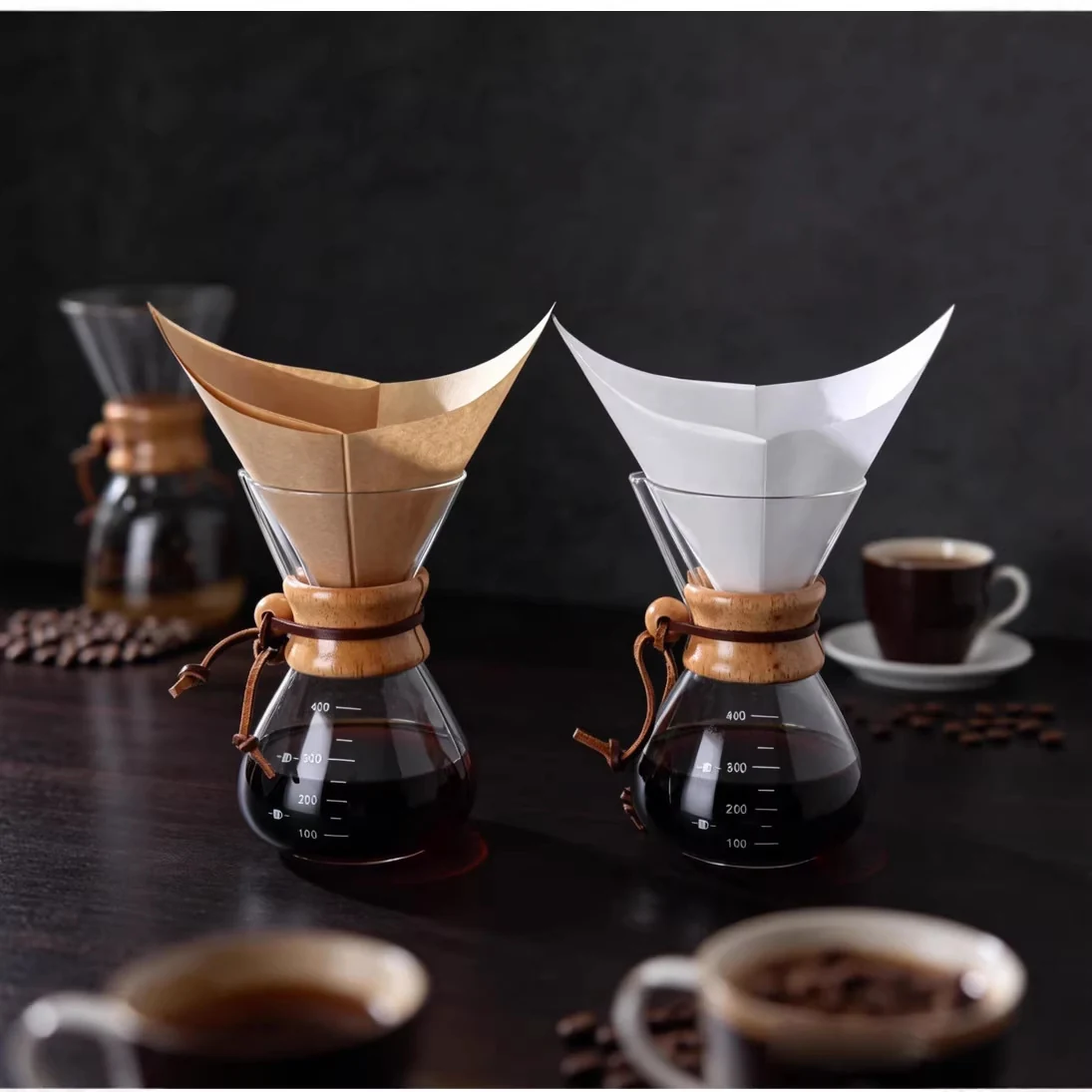 Brown and white folded square coffee filters placed in two glass brewers.