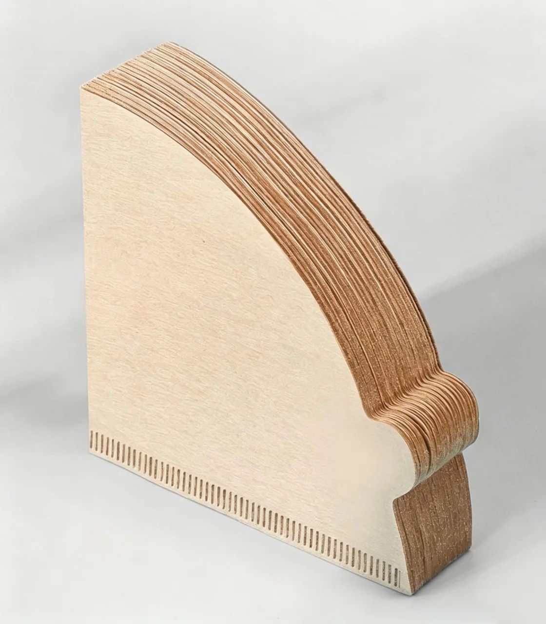 Stack of brown fan-shaped coffee filter papers with a crimped edge