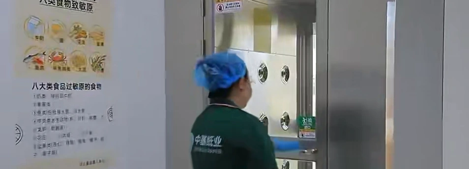 Worker wearing a hair cover at the factory air-shower entrance.